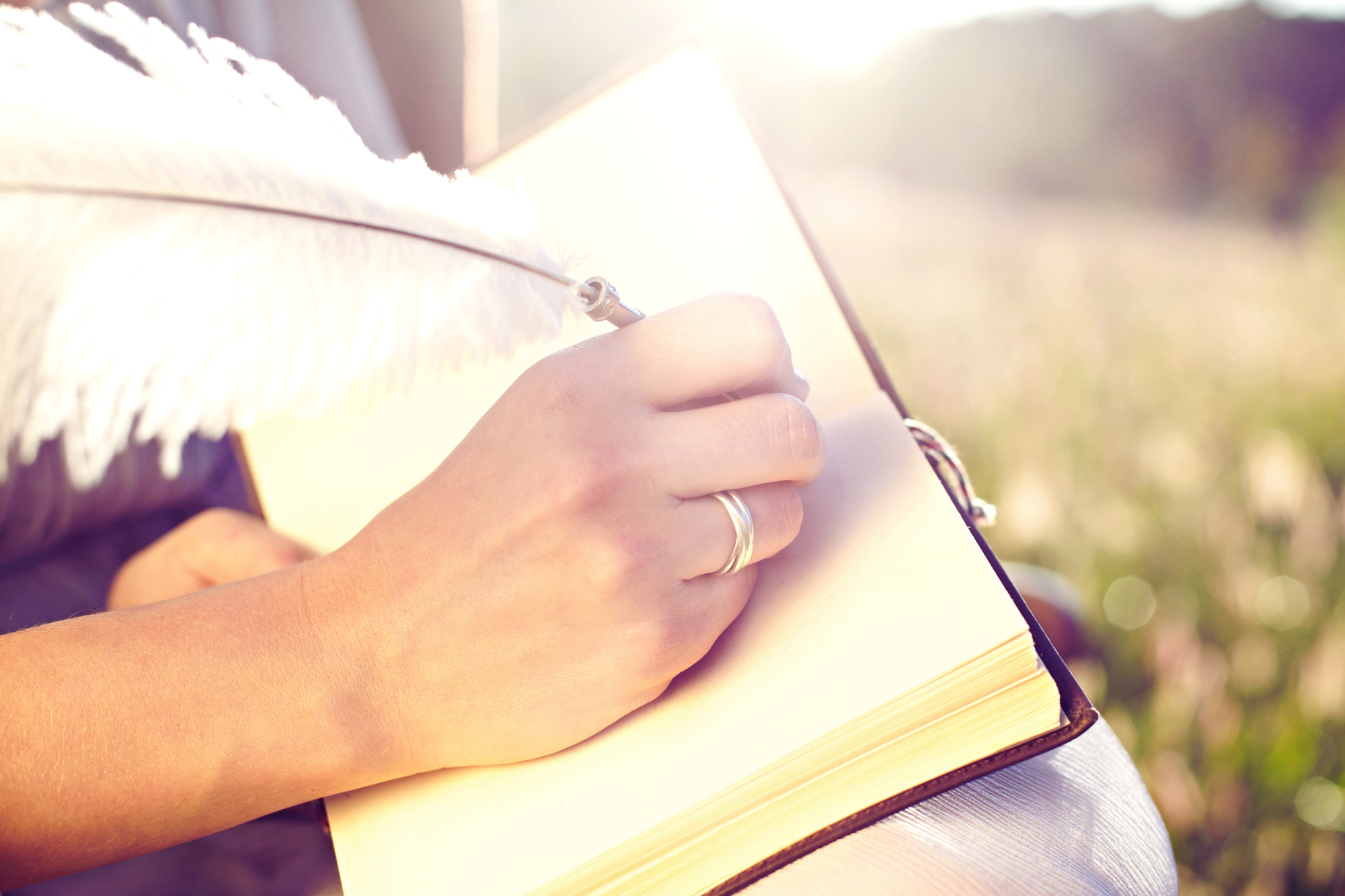 6. Prämenopause Achtsamkeit (3.2) Frauenhand mit weißer Schreibfeder und Notizbuch